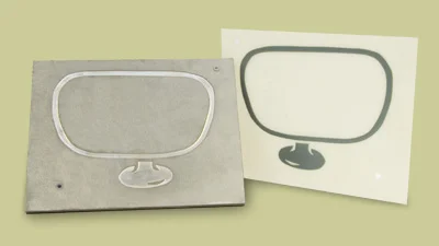 Emboss die beside its finished impression on white stock